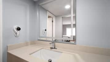A bathroom with a white sink, a mirror, and a security camera.