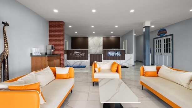 Een hotel lobby met twee banken, een receptiebalie, een open haard en een bordje voor de ontbijthoek.