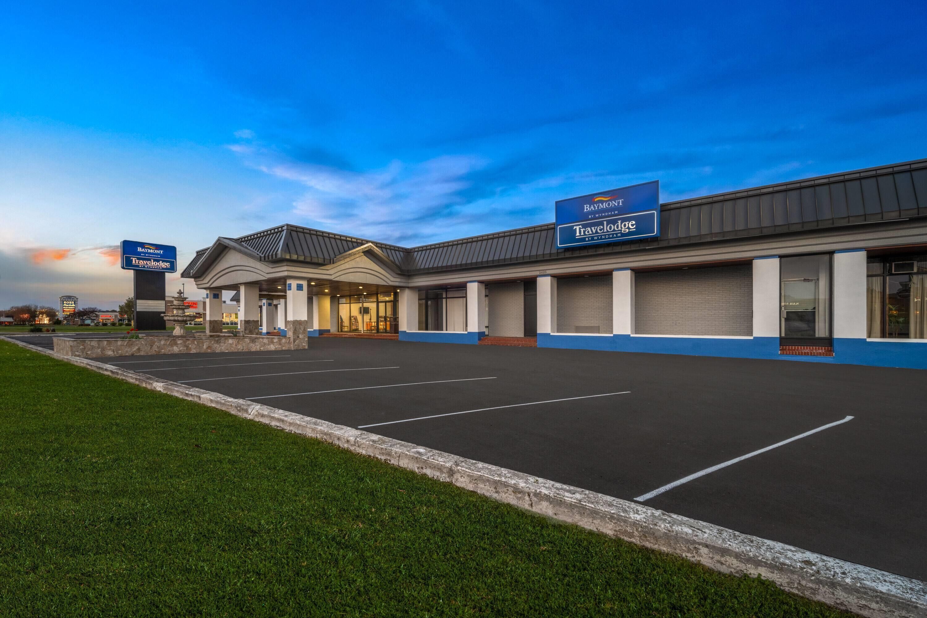 A hotel with a Travelodge sign, a parking lot, and a grassy area.