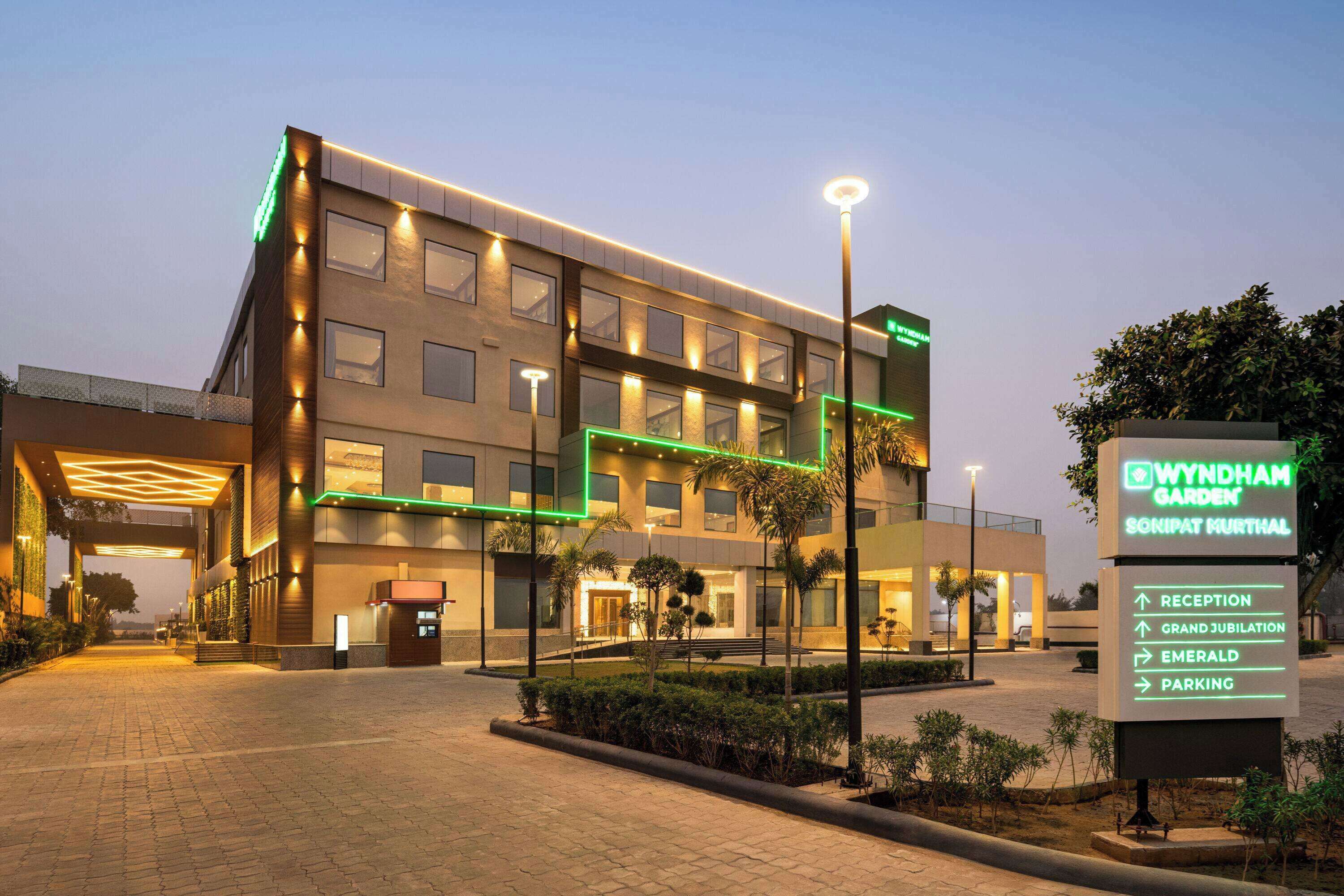 A modern hotel with a sign indicating amenities like reception, grand jubilation, emerald, and parking.