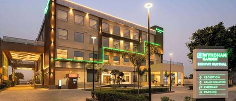 A modern hotel with a sign indicating amenities like reception, grand jubilation, emerald, and parking.