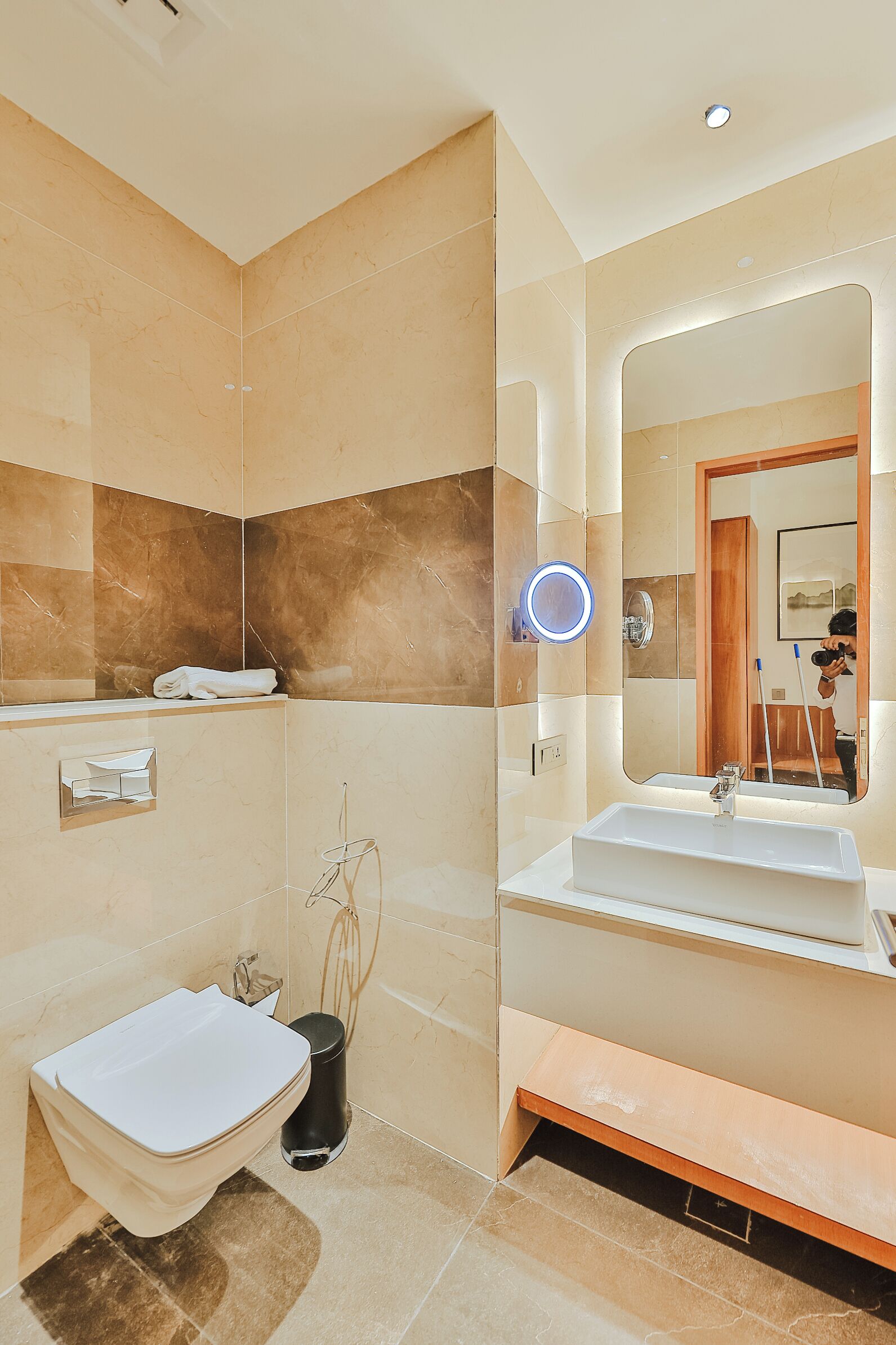 A modern bathroom with a white sink, a mirror, and a toilet.