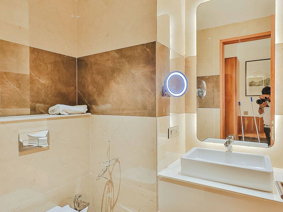 A modern bathroom with a white sink, a mirror, and a toilet.
