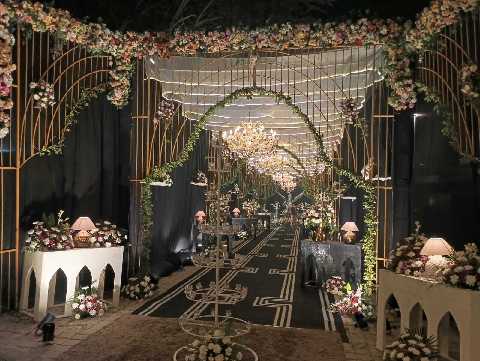 An indoor event space with a central aisle, floral decorations, and a chandelier.