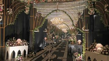 An indoor event space with a central aisle, floral decorations, and a chandelier.
