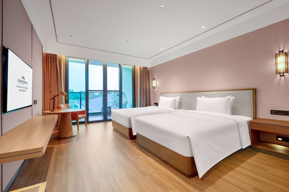 Une chambre d’hôtel avec deux lits, un bureau, une chaise, une télévision et un balcon avec vue.