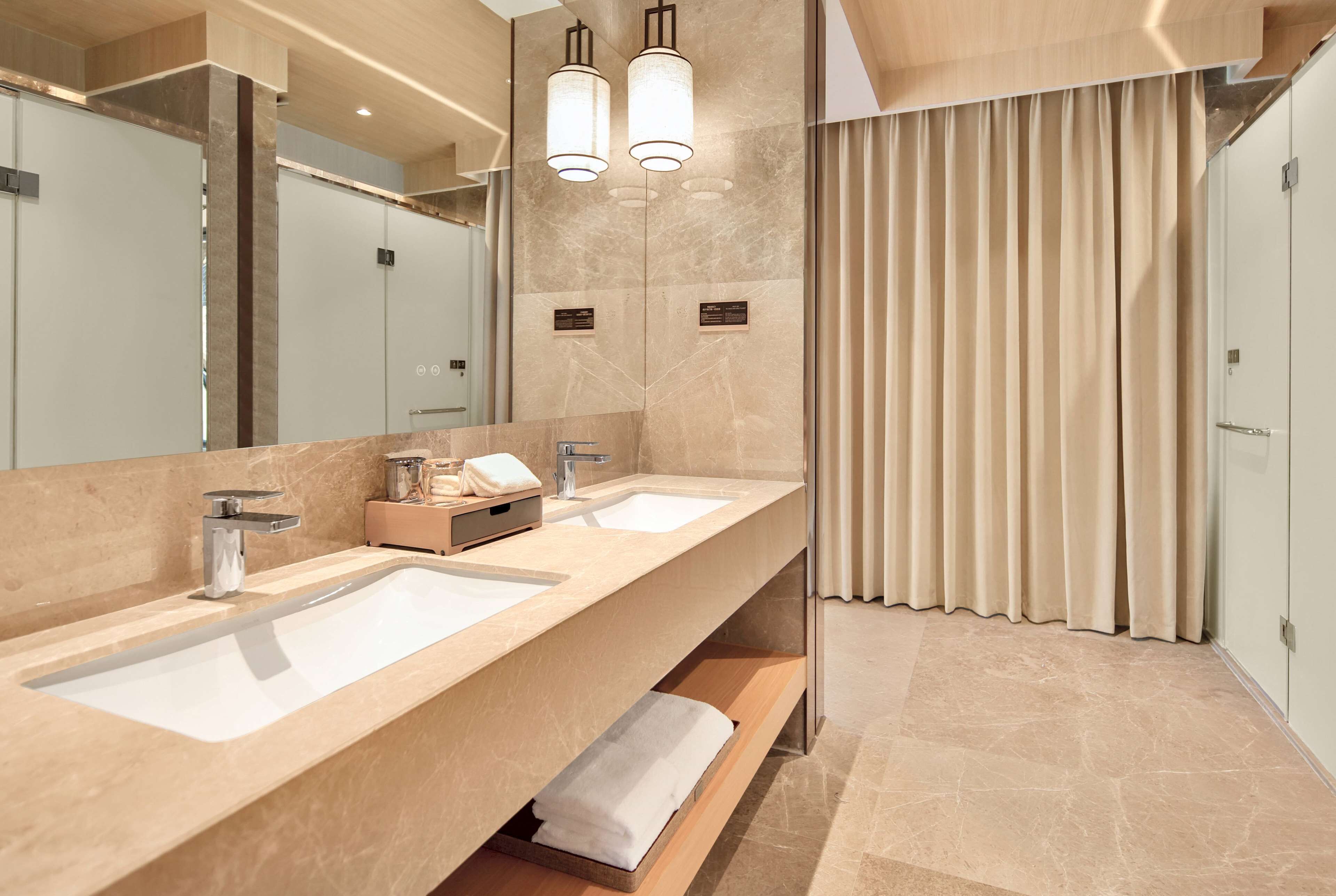 Une salle de bain moderne avec deux lavabos, un grand miroir et un espace douche.