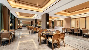 A spacious dining area with multiple tables and chairs, a polished marble floor, and a modern ceiling design.