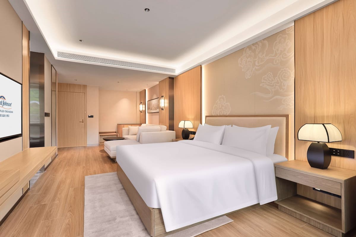 Une chambre d’hôtel moderne avec un grand lit, des tables de chevet, un bureau et une télévision.