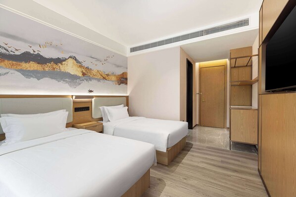 Ein Hotelzimmer mit zwei Betten, einem großen Gemälde an der Wand, einem Fernseher und Holzmöbeln.