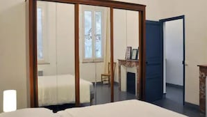 A bedroom with a bed, a wardrobe, a chair, and a door.