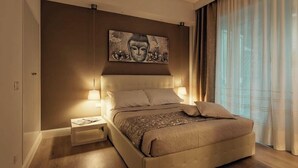 Ein modernes Schlafzimmer mit einem großen Bett, Nachttischlampen, einem Beistelltisch und einem an der Wand hängenden Kunstwerk.
