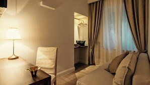 Ein Hotelzimmer mit einem Bett, einem Nachttisch mit Lampe, einem Sessel, einem Kleiderschrank und einem Spiegel.