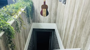 Eine Treppe mit einer gitarrenförmigen Leuchte darüber, umgeben von Grünpflanzen und einer Holzverkleidung.