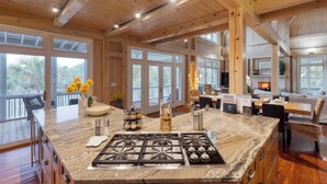 Una cocina amplia con una isla grande, vigas de madera en el techo y ventanas grandes que ofrecen vistas al exterior.