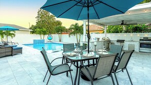 An outdoor patio with a dining table, chairs, and a large umbrella.