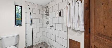 Et badeværelse med bruser, toilet og en trædør.