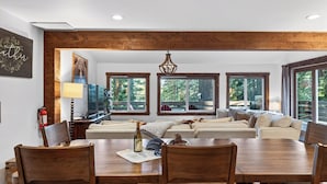 A spacious living room with a wooden ceiling, large windows, a dining table, and a sofa set. - Washoe Way by Avantstay Luxury Tahoe Retreat A+ Location w/ Beach Access (Tahoe City)