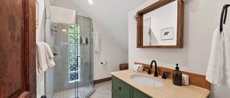 A bathroom with a double sink, a mirror, and a shower.