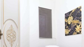 A bedroom with a bed, a wardrobe, a window, and a wall with a tropical leaf pattern.
