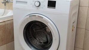 A front-loading washing machine with a control panel, a digital display, and a top-loading section.