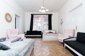 Quarto moderno com cama grande, duas cadeiras, um sofá e uma janela com cortinas.