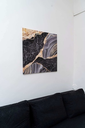 Quarto com sofá preto e uma obra de arte com padrão de mármore na parede.