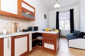A compact kitchen with wooden cabinets, a microwave, and a small dining area.