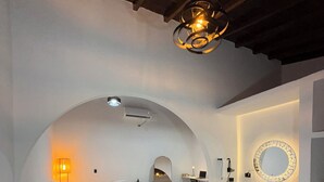 Een moderne slaapkamer met een bank, een bed, een bureau en een badkamer met een wastafel en spiegel.