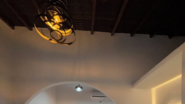 Een moderne slaapkamer met een wit bed, een bank, een spiegel en een opvallend plafond met bogen.