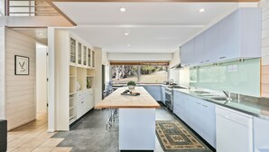 A modern kitchen with a central island, white cabinetry, and a view of the outdoors. - Silvertop Apartment capturing the beautiful mountain and lake views (Crackenback)