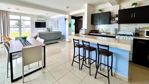 Une cuisine moderne dotée d’un îlot central, de tabourets de bar, d’une cuisinière encastrée et de meubles de rangement aux couleurs sombres.