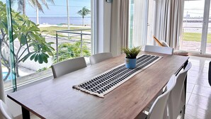 Un espace repas avec vue sur la mer, une plante en pot et une table au design moderne.