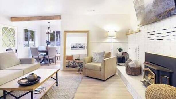 A living room with a sofa, armchair, coffee table, and a fireplace. There is a dining area with a table and chairs visible through an open door. - NEW! Hello Big Bear: Billiards, Airhockey, Firepit (Big Bear Lake)