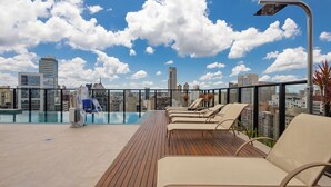 Ein Poolbereich auf dem Dach mit Liegestühlen und Blick auf die Stadtlandschaft.