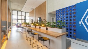 Eine moderne Bar mit einer Holztheke, Barhocker und Topfpflanzen.