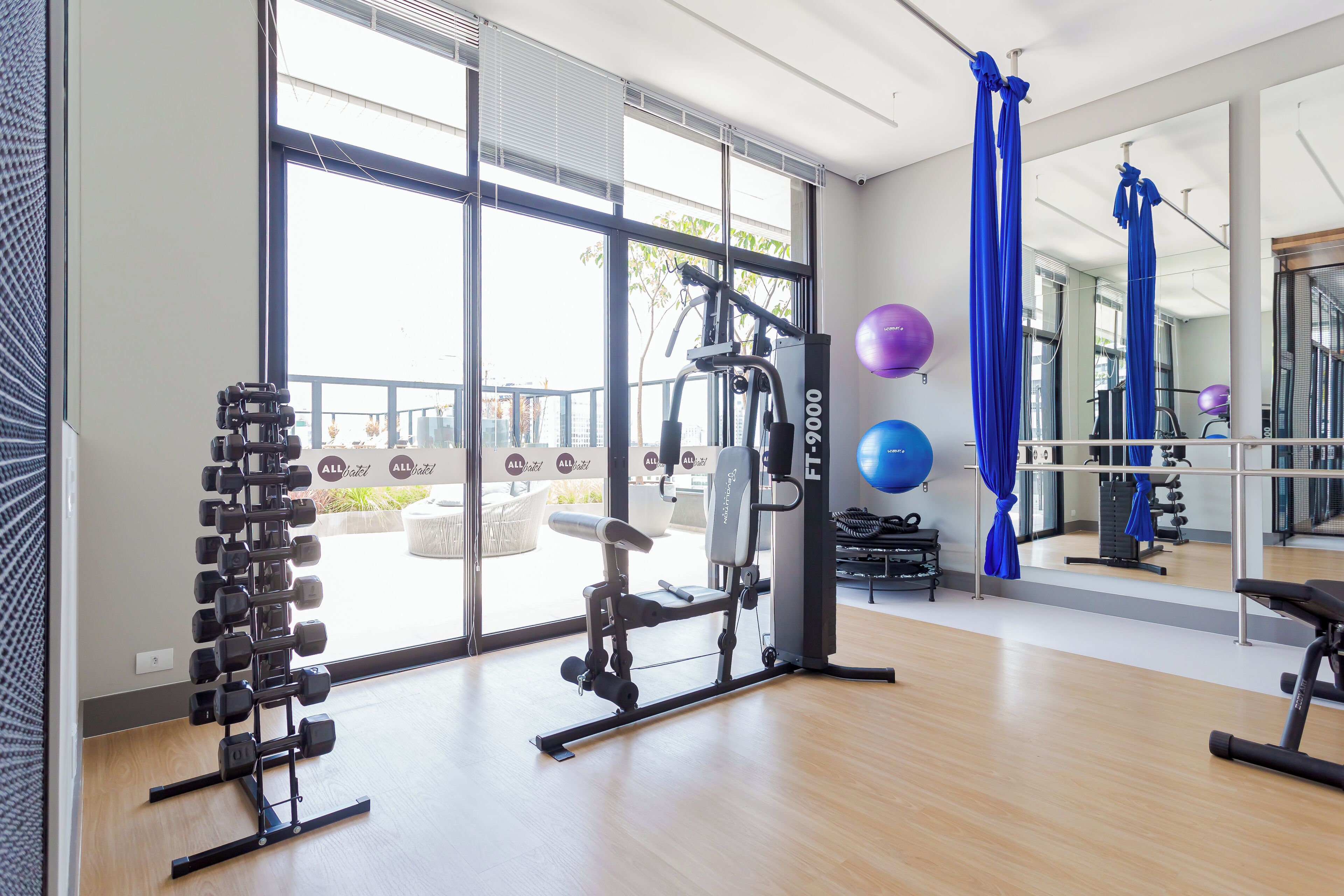 A gym with exercise equipment, large windows, and a view of the outdoors.