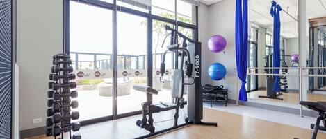 A gym with exercise equipment, large windows, and a view of the outdoors.