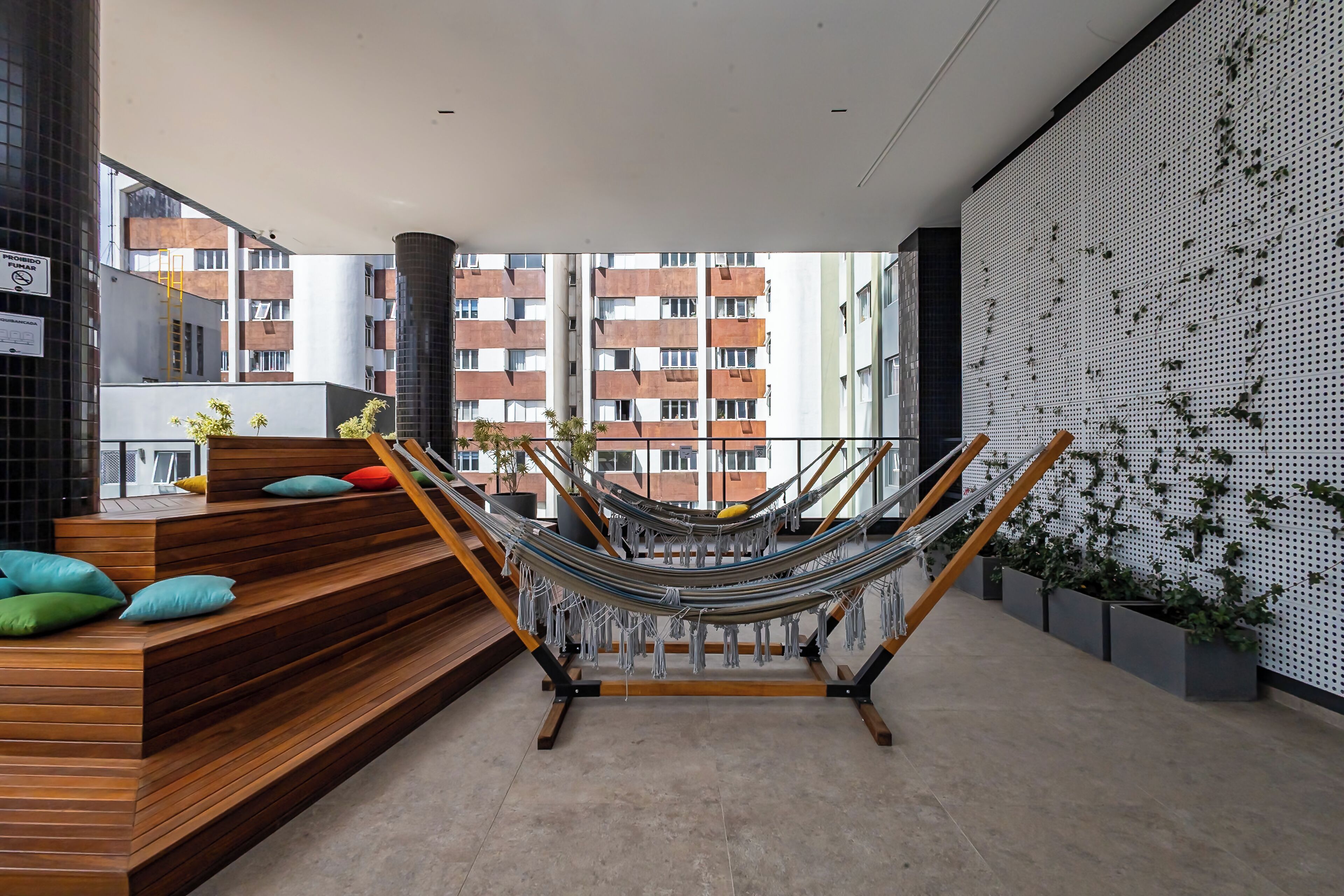A modern interior with a hammock, wooden steps, and a view of buildings.