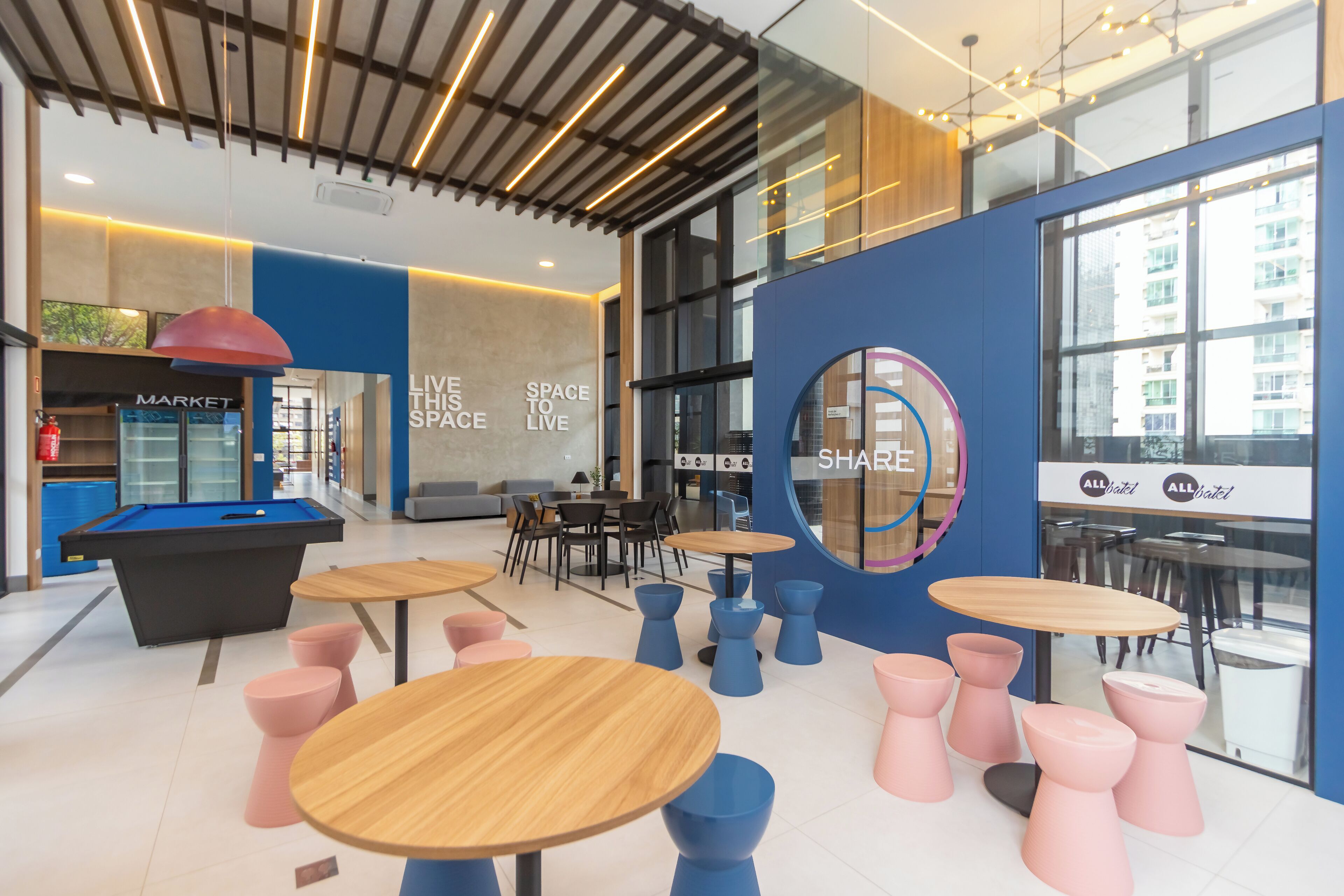 A modern indoor space with a pool table, multiple seating areas, and a large circular window with the word "SHARE" on it.