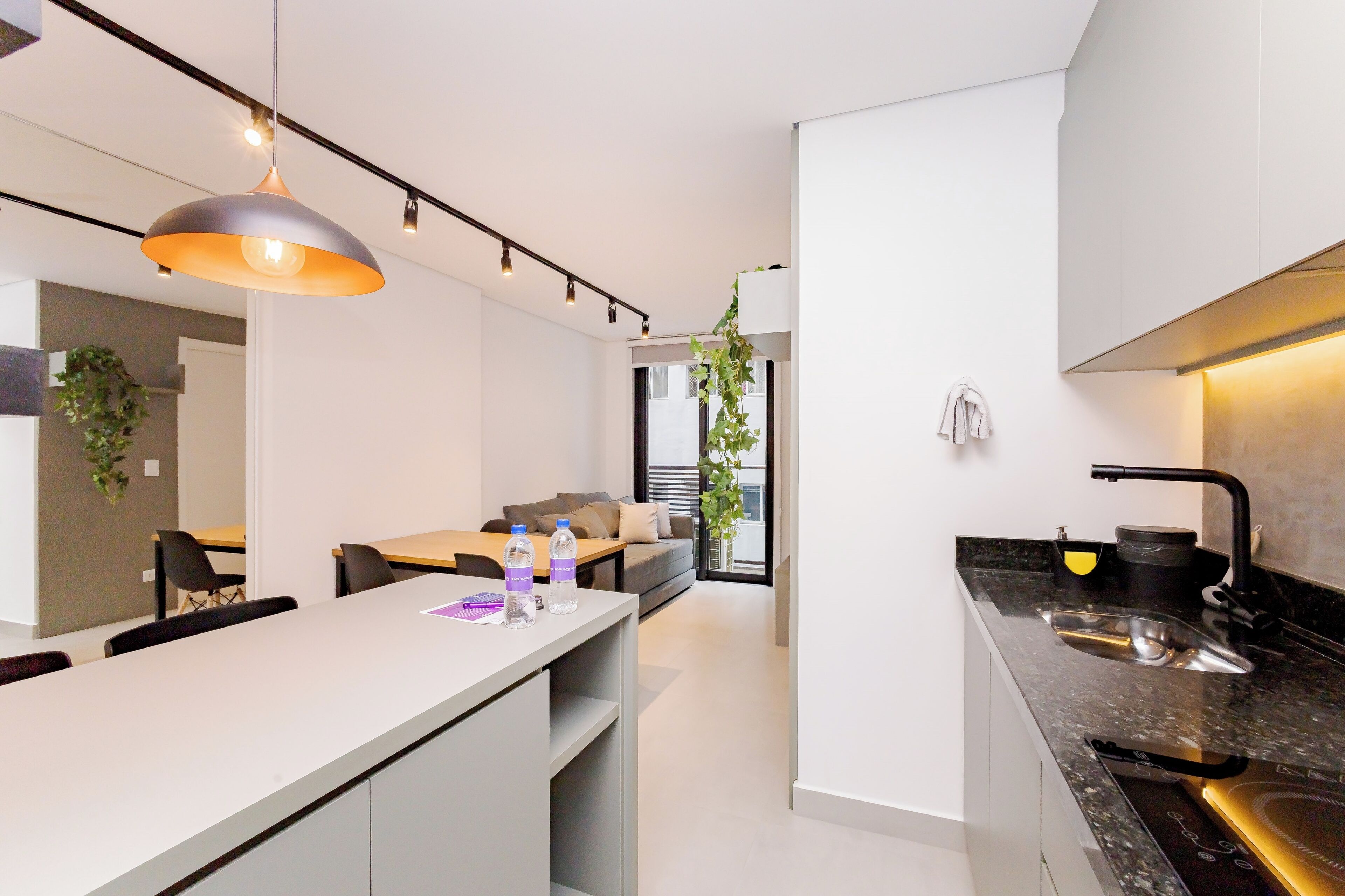 Una cocina moderna con una isla central, un área de comedor con sofá y un ventanal que proporciona luz natural.
