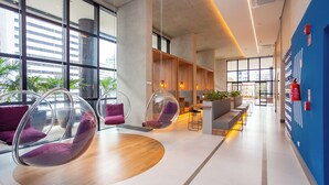 Eine moderne Lobby mit großen Fenstern, Sitzbereichen mit transparenten Stühlen und einer blauen Akzentwand.