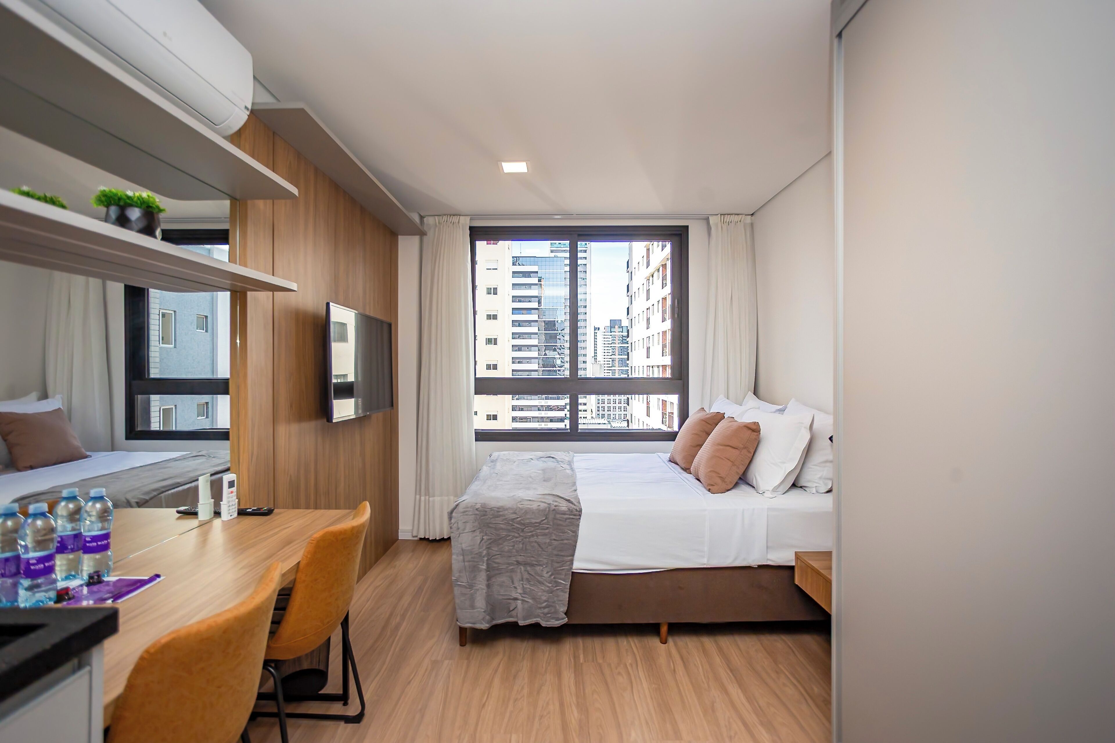 Una habitación de hotel moderna con cama, escritorio y televisor.