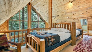Een houten slaapkamer met een bed, een stoel en grote ramen.