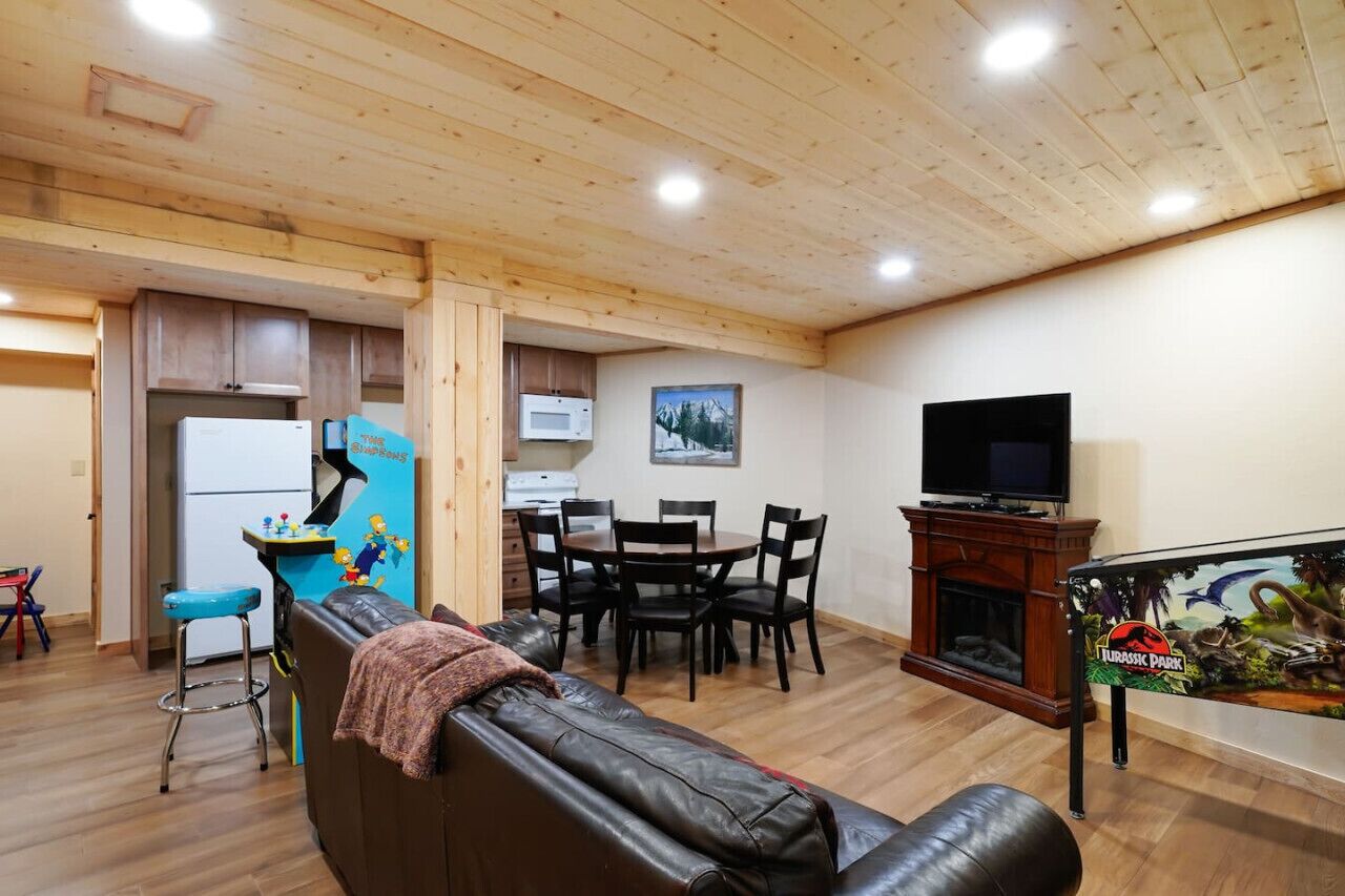 A living room with a leather sofa, a dining table with chairs, a kitchen area with a refrigerator, microwave, and a small bar area.