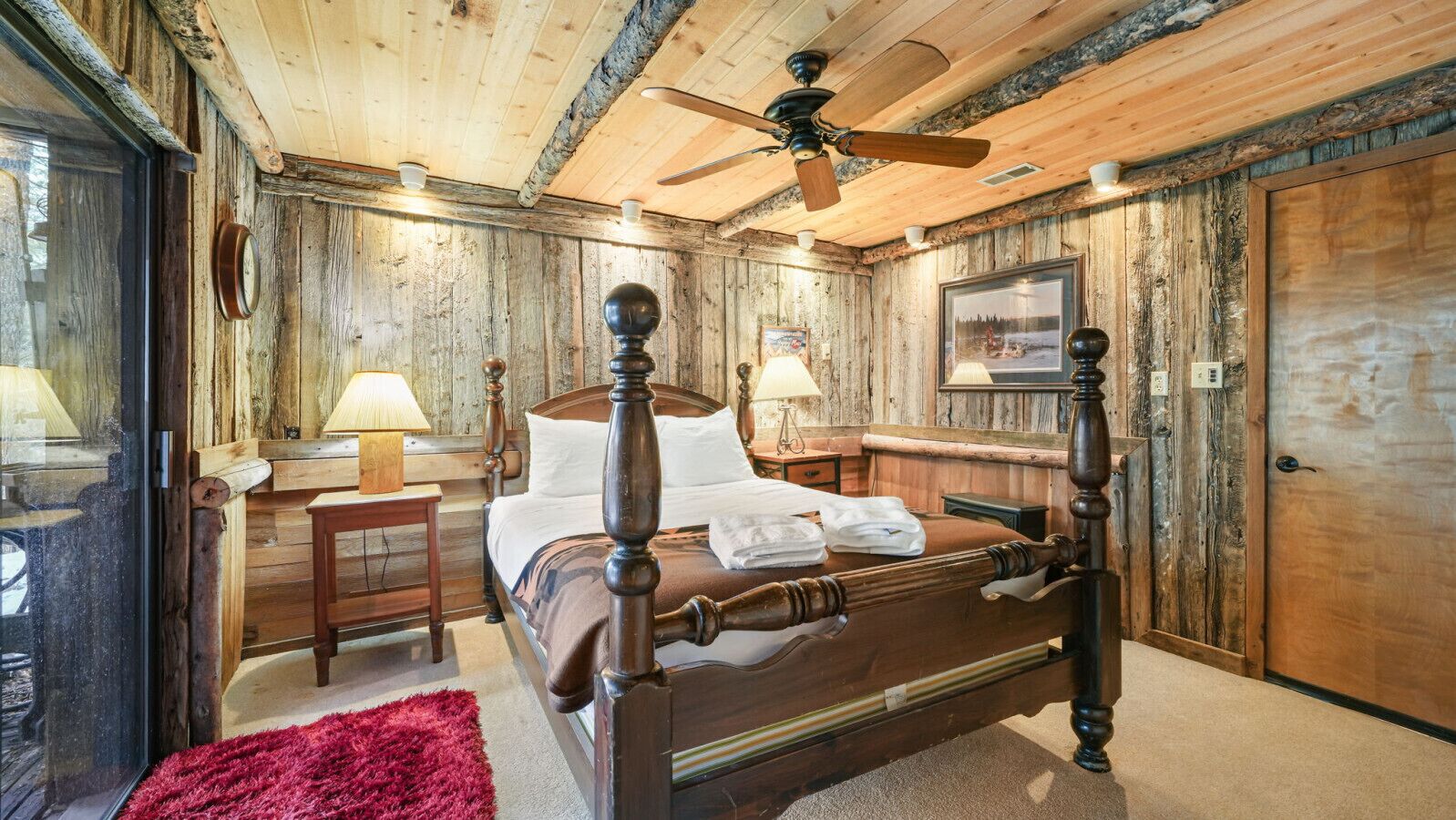 Ein Zimmer mit Holzboden, einem Bett, einem Schreibtisch und einem Stuhl.