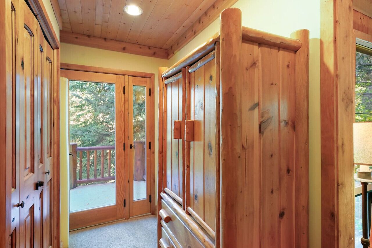 Un couloir intérieur aux murs en bois, avec une porte en verre donnant sur une terrasse extérieure.