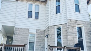 A two-story house with a stone facade, a front porch with a wooden railing, and a set of stairs leading to the entrance. - Downtown EVV Studio / Chandler C (Evansville)