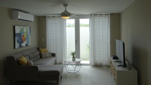 Un soggiorno con divano, tavolino, televisore e ventilatore a soffitto.