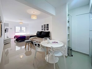 A modern, well-lit living room with a dining area, a sofa, and a TV.